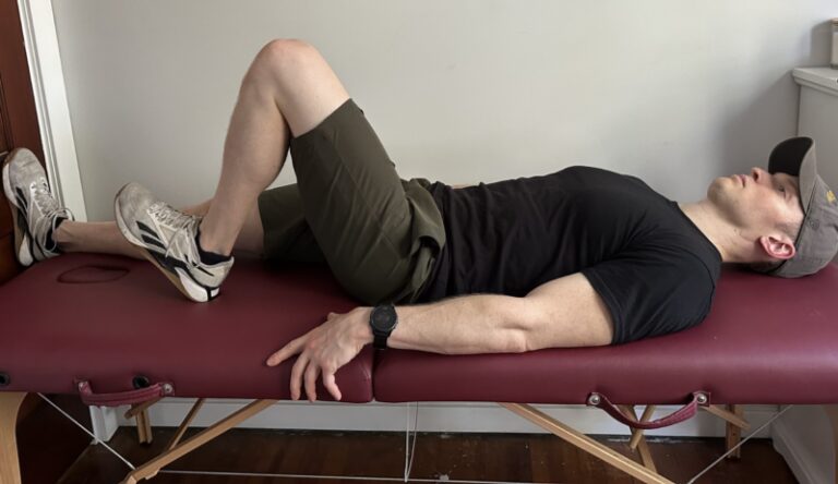 Demonstration of an active heel slide, lying on a massage table