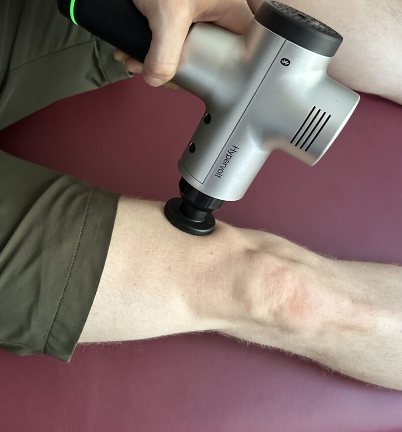 Me using a Hypervolt massage gun on the vastus medialis of my quad muscle to prevent knee pain