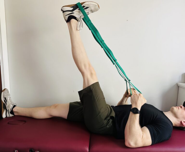 Demonstrating a hamstring stretch with a strap to restore full knee extension after a knee replacement.