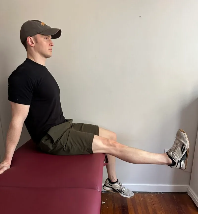 Demonstrating the long arc quad exercise to increase the strength of the quadriceps after a knee replacement.