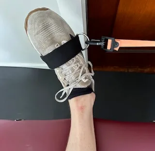 I am demonstrating ankle inversion with a resistance band to strengthen the arch of my foot.
