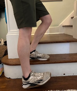 Performing a lateral step down, one of the best at home strengthening exercises of the quad muscle for treating knee pain.