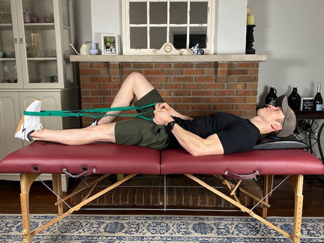 demonstrating a calf stretch with a strap to increase gastroc flexibility for a torn meniscus