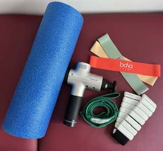 A foam roll, hypervolt massage gun, stretching strap, ankle weight, and bands. All equipment need to treat knee pain from home.
