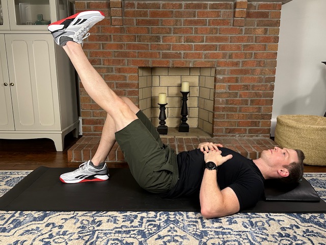 demonstrating a straight leg raise exercise while lying on a thick yoga mat to treat a torn meniscus