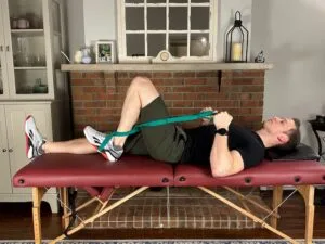 Demonstrating a heel slide with a strap exercise to restore full knee flexion after a knee manipulation