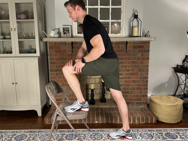 Demonstrating knee flexion on a chair exercise to improve functional knee range of motion