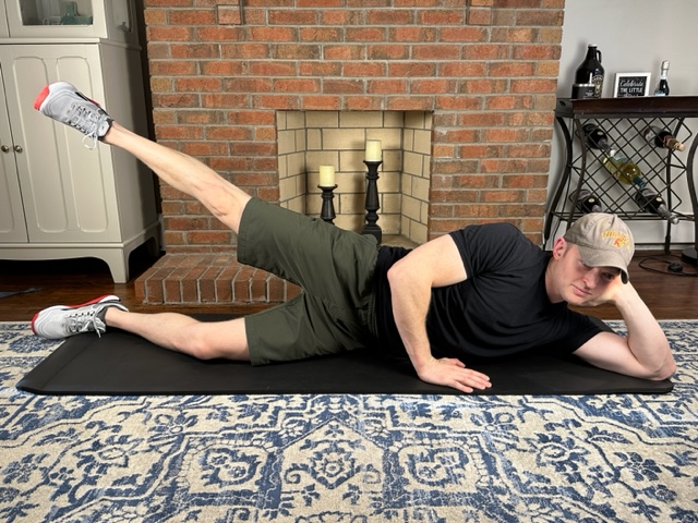 Demonstrating a sidelying hip abduction exercise to strengthen the lateral hip muscles for treating gluteal tendinopathy