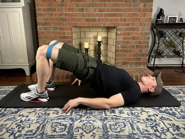 Demonstrating a bridge with band exercise to strengthen the butt and hip muscles for the treatment of Osgood-Schlatter Disease