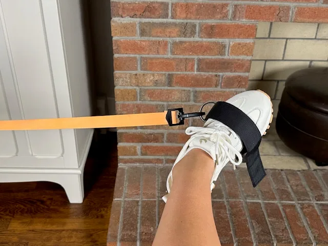 demonstrating ankle inversion with band to strengthen posterior tibialis