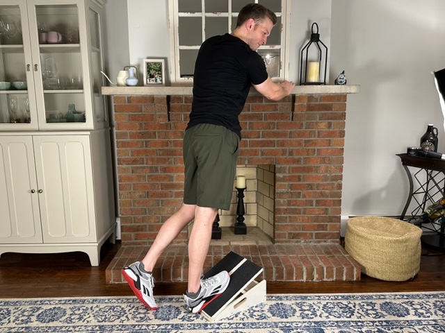 Demonstrating the calf stretch on a slant board exercise to relieve tight calves after meniscus repair