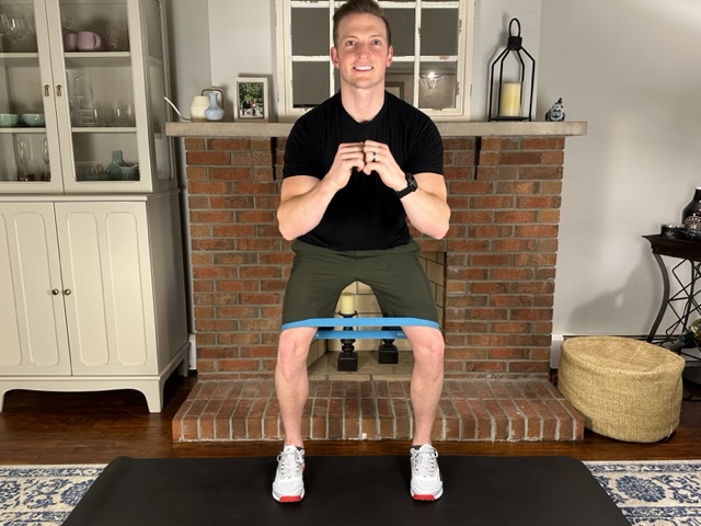 Demonstrating sidesteps with a band to strengthen the glutes to reduce knee pain