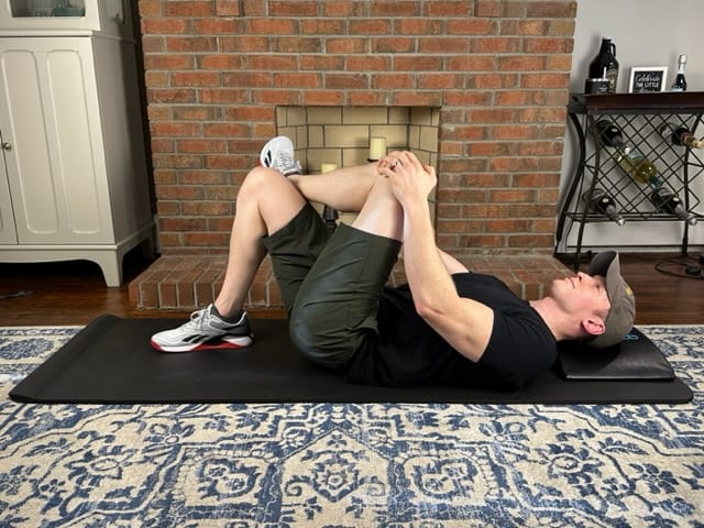 Physical therapist demonstrating the piriformis stretch for knee and hip tension relief after long drives