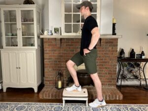 Physical therapist demonstrating step-ups for stair-specific quad and glute activation in knee rehab