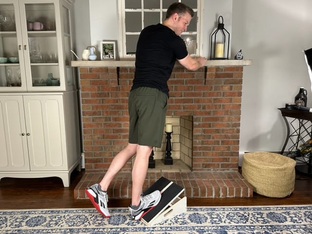 Standing calf stretch on slant board performed by a physical therapist for improved mobility and posture