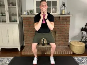 Goblet squat exercise for LCL sprain demonstrated by a physical therapist in his home; strengthens legs while improving alignment