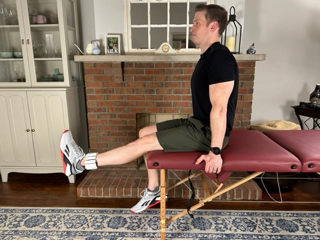 Physical therapist demonstrating long arc quad exercise for knee clicking and popping; builds knee strength and extension control